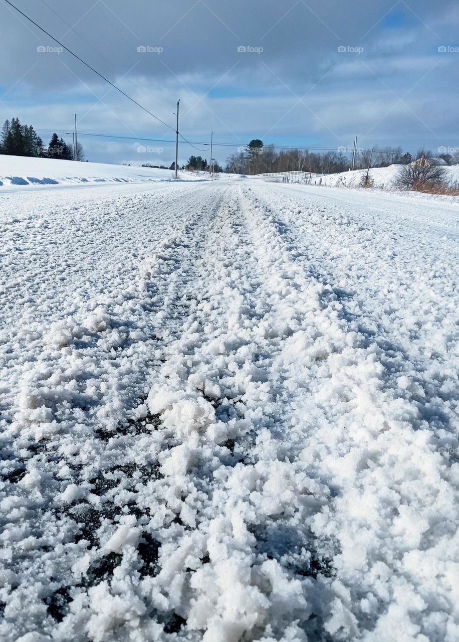 Driving after the storm!  Tire tracks on a snow covered small town road in New England after a snowstorm.