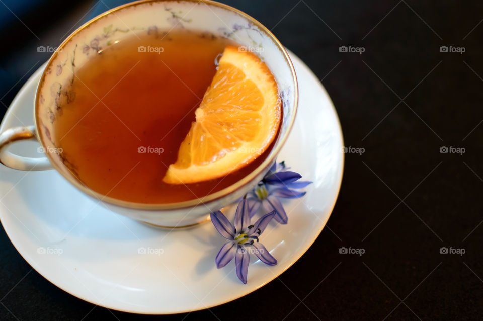 Slice of orange in vintage antique tea cup and little purple blue lily flowers Scilla siberica healthy lifestyle tea time  image 