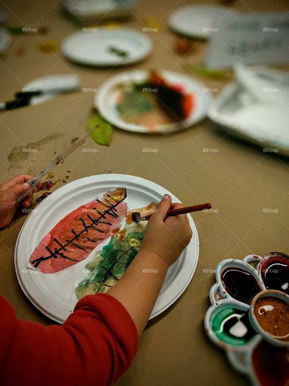A small child paints autumn leaves
