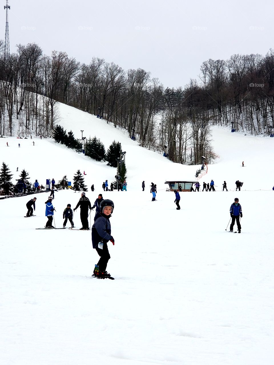 Young boy and people snowboarding and skiing downhill in the snow