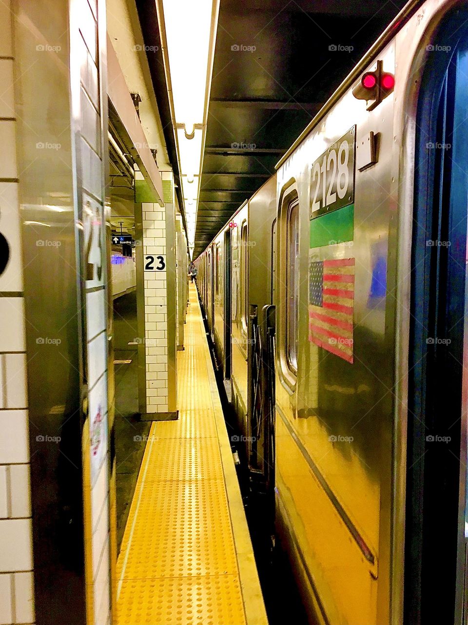 An incoming subway train at the 23rd St station. The special charm of this image is in the silver sheen of the subway cars reflecting with metallic elements in the station and the narrow angles of an extended perspective. 2022. Hypnotic Productions