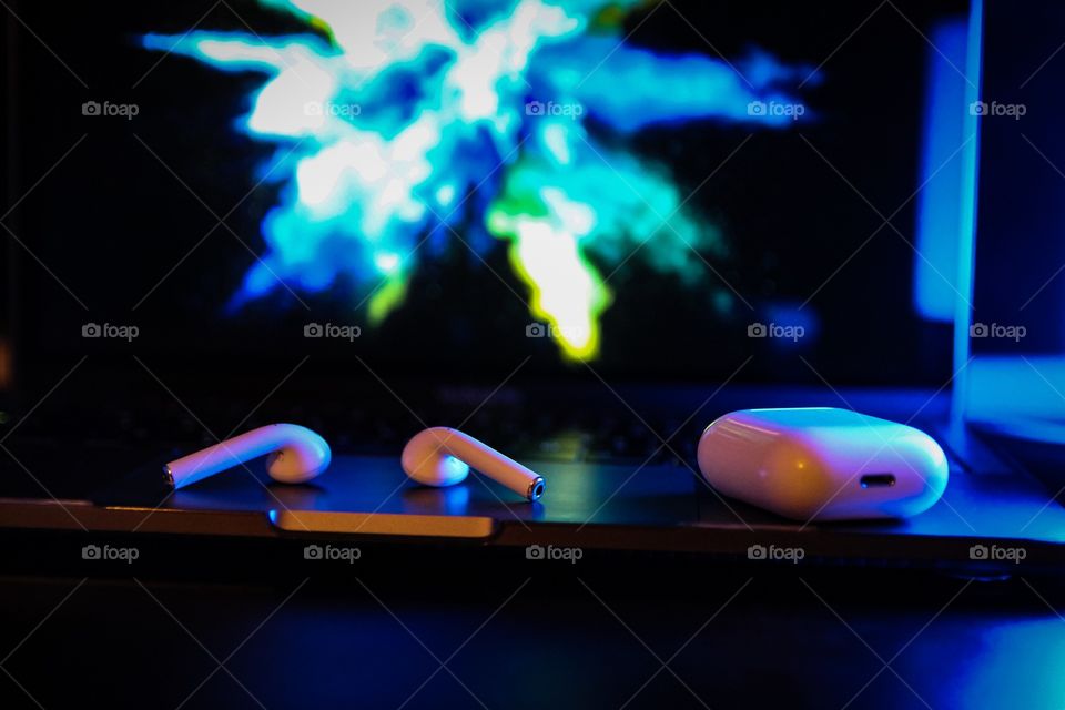 Air pods on a desk with blue lighting in the background 