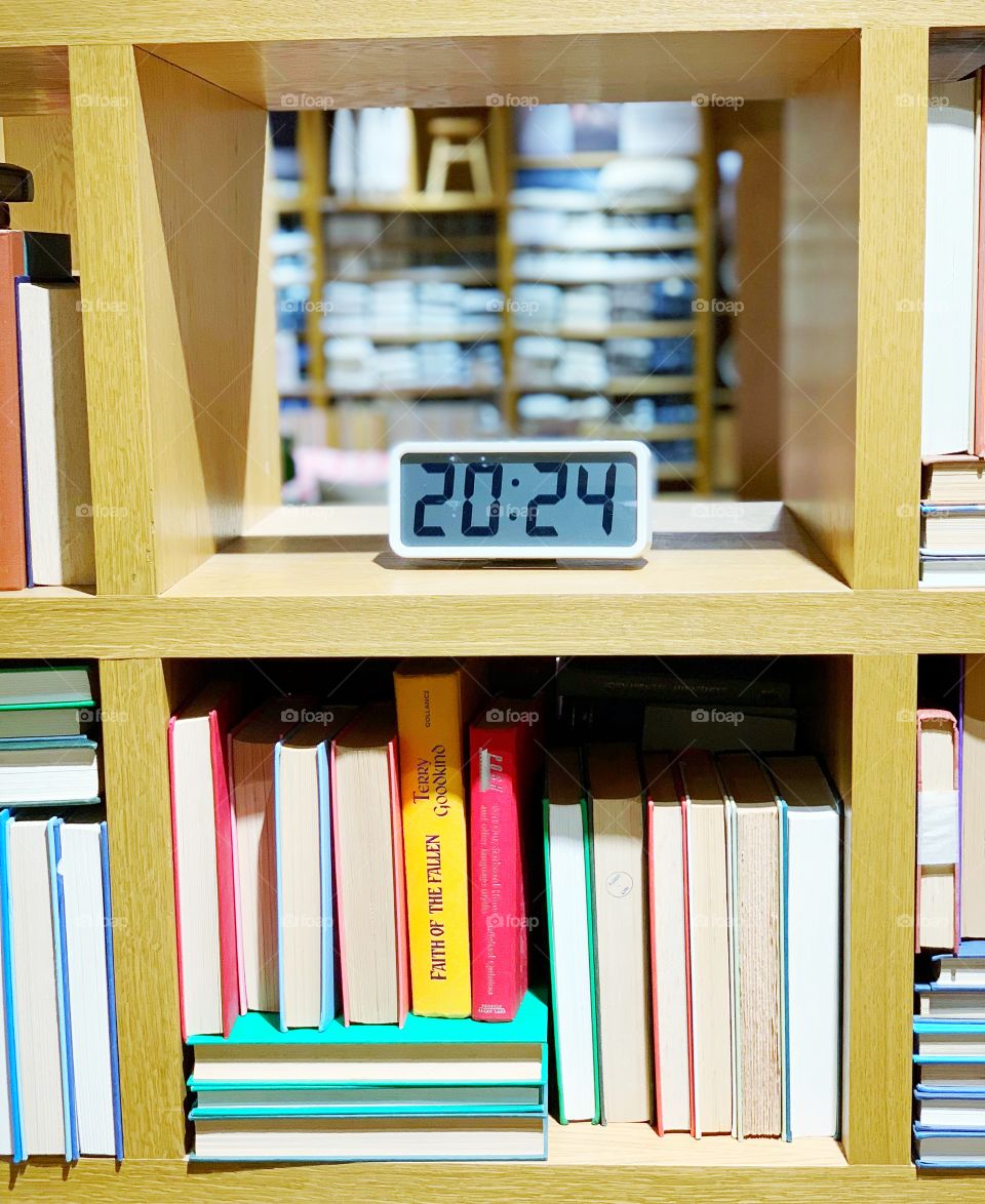 Bookcase with digital clock and colourful books 