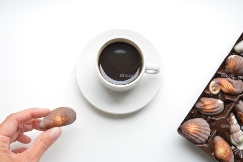 cup of coffee ☕ and chocolate candy in the hand top view on a white background, beautiful texture, morning routine