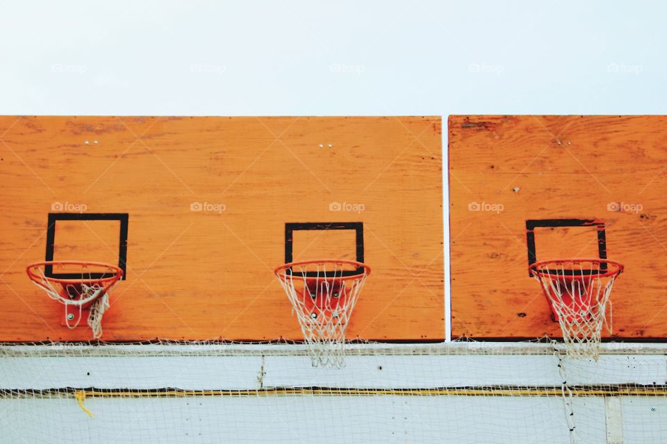 Basketball hoops with nets on weathered, orange, playwood backboards