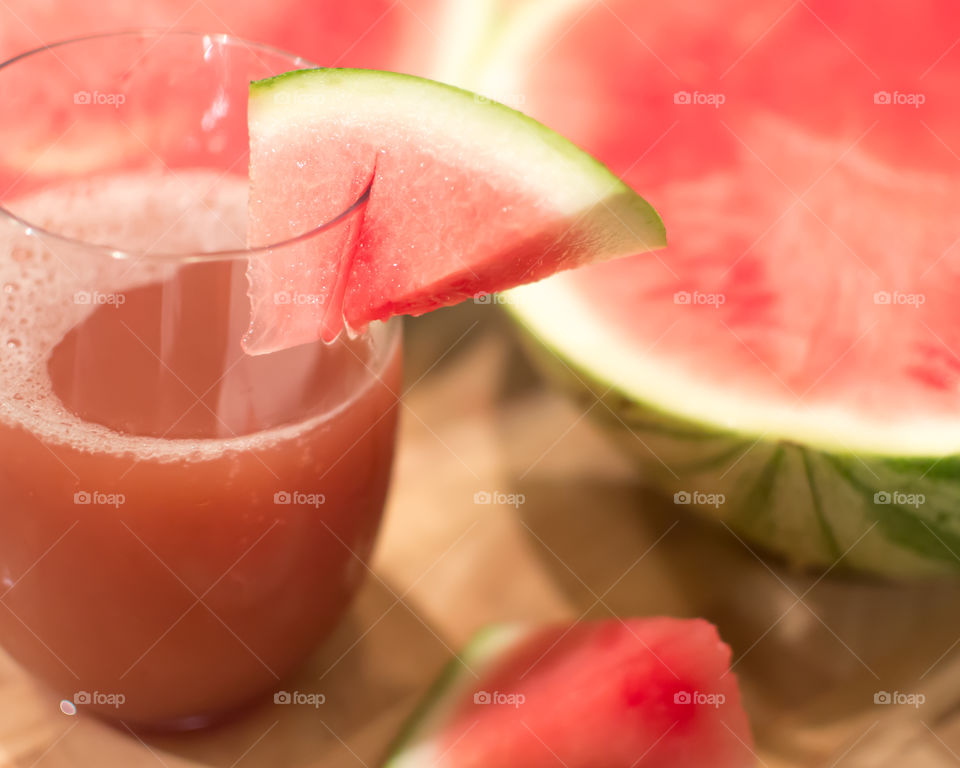 Closeup of glass of pink homemade fresh juice with watermelon garnish and sliced seedless watermelon for summertime party healthy drinks ideas and wellness background 