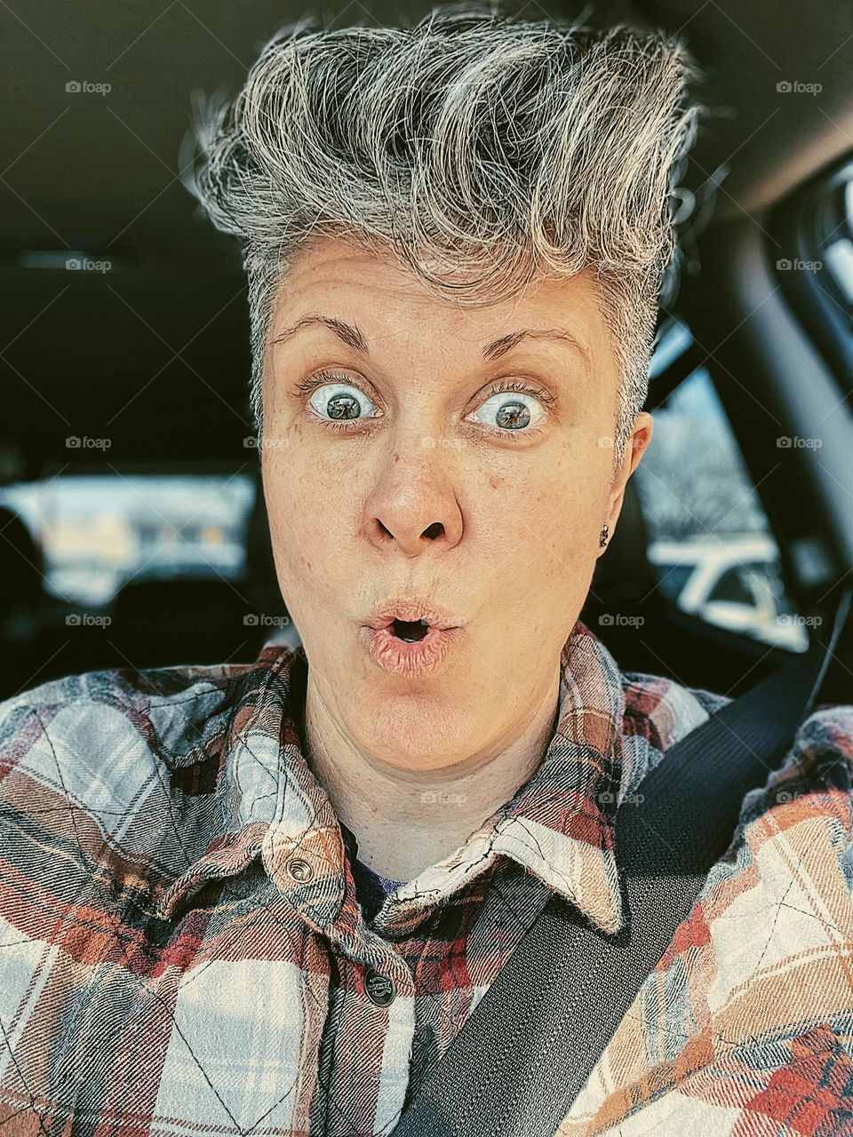 Surprised woman is driving in car, surprised expression on woman’s face, surprised while driving a car, surprised facial expression on woman, facial expressions showing emotion