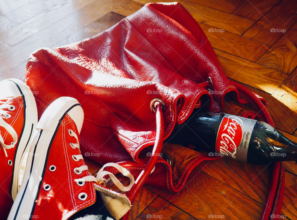 Diet Coke in red bag with red sneakers on hardwood floor.