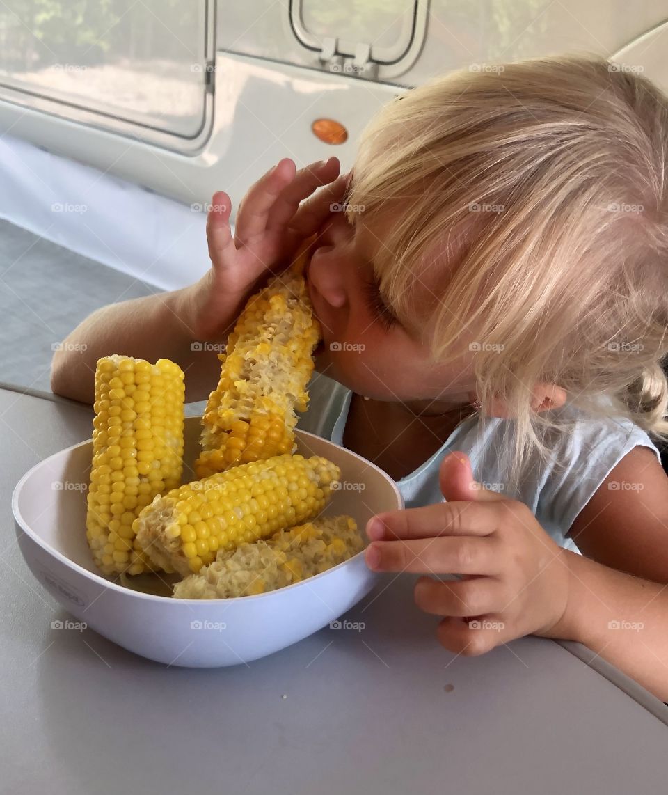 child eats green boiled corn