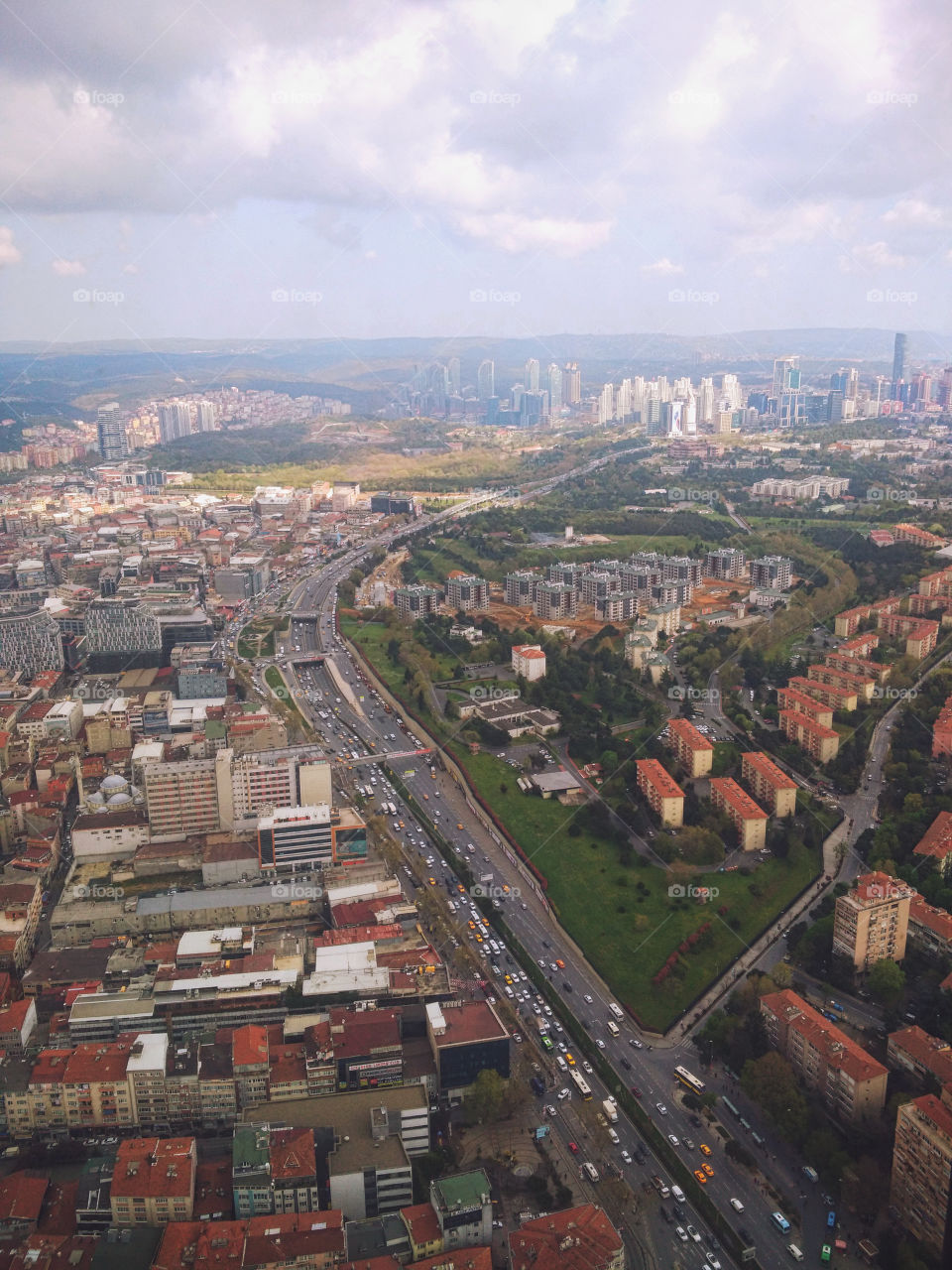A view from the window of a high-rise building on a multi-million dollar city with roads, avenues, skyscrapers and houses with red roofs. Urban studies.