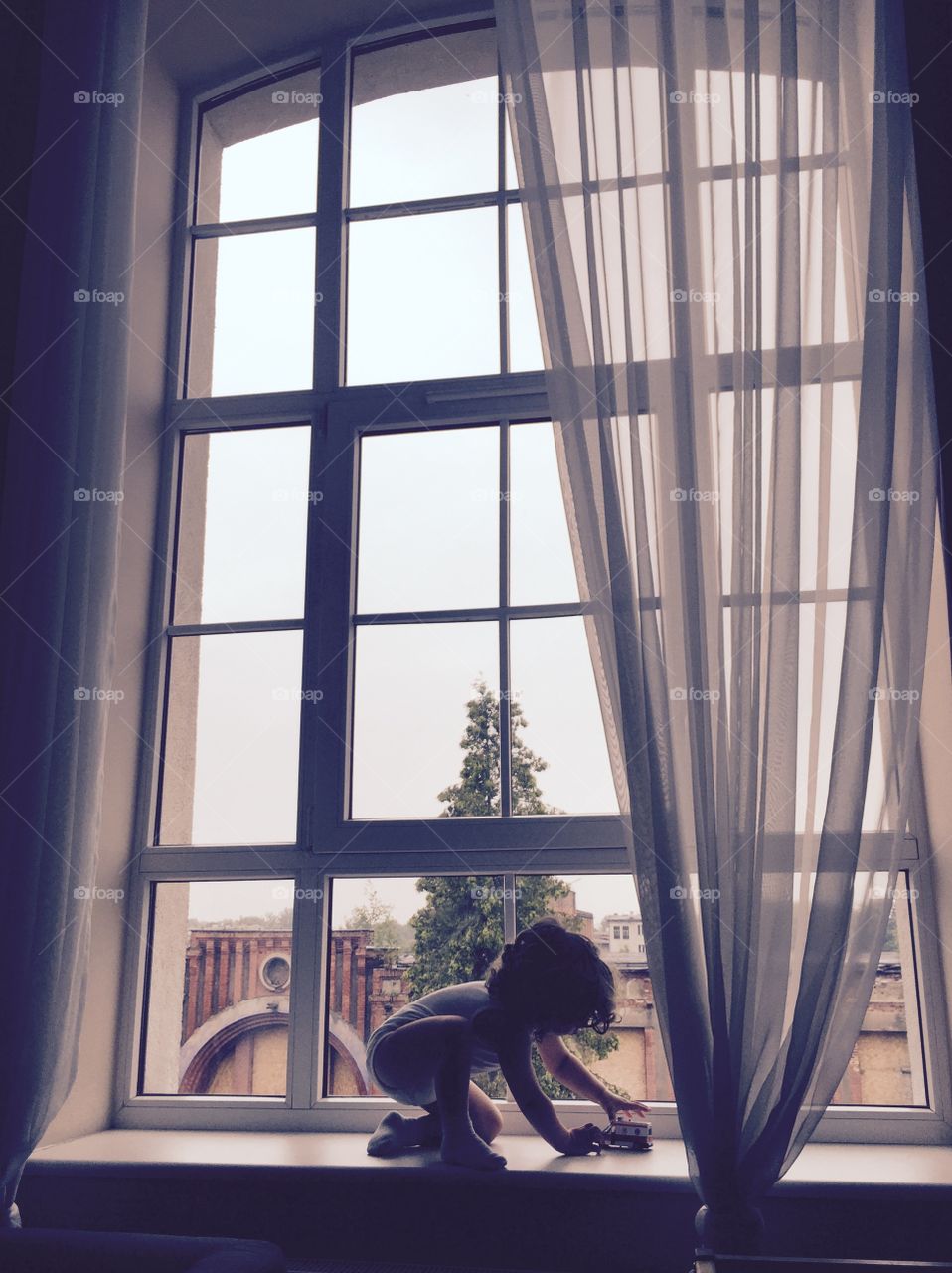 Cute boy playing with toy on window sill