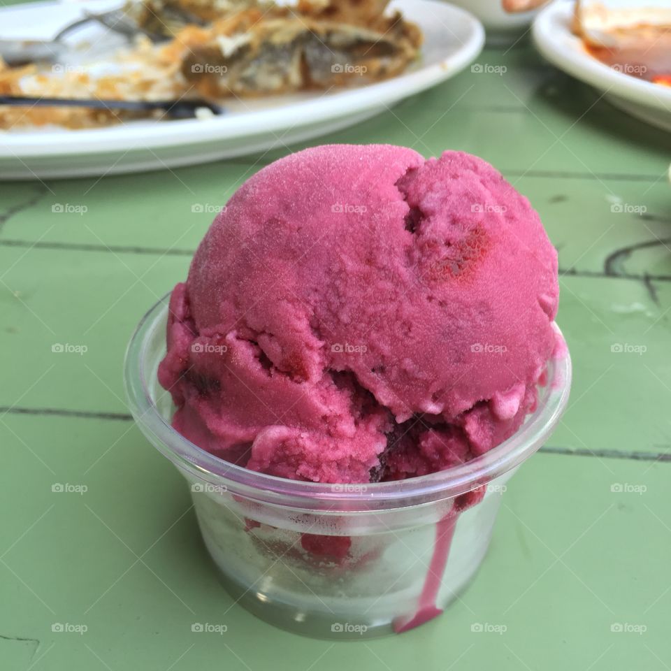 A scoop of rasberry sorbet in a colorful setting great for any use.