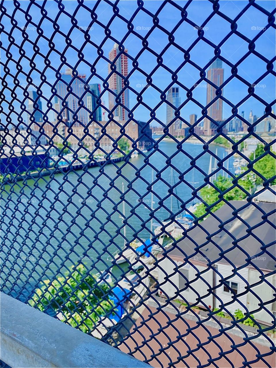 The “East River” at “Newtown Creek” seen through the fence from the pedestrian lane of the “Pulaski Bridge” on a hazy and very hot summer day in Mid July 2022. Hypnotic Productions