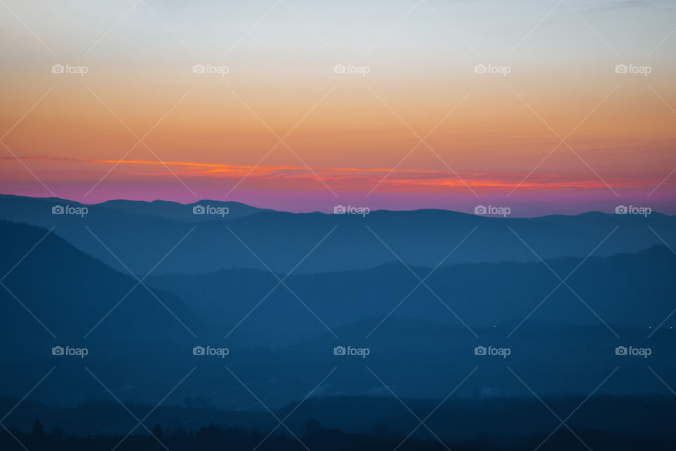 Layers of mountains in blue color with orange sky