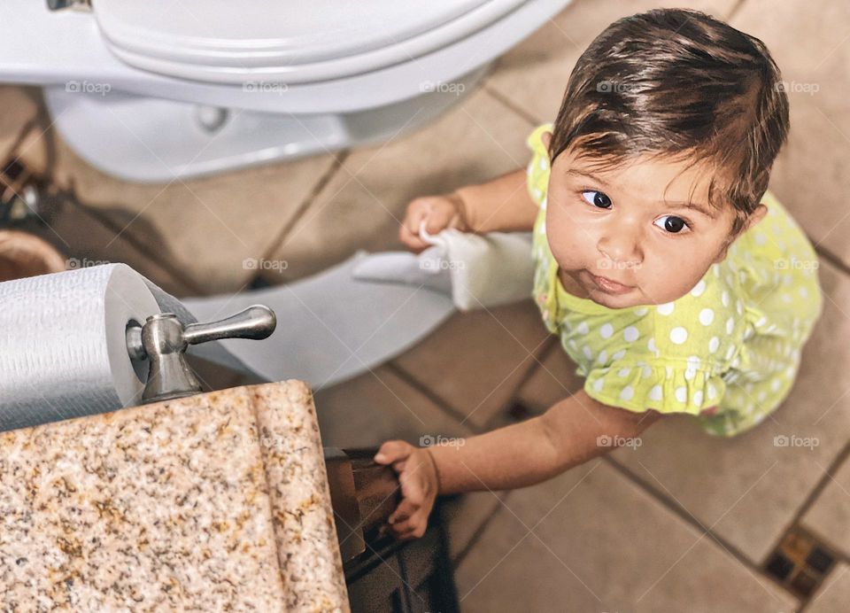 Baby is surprised by mother interrupting their mess making, baby girl unrolls toilet paper and tries not to get caught by parent, baby makes a mess, surprises for mommy, baby surprises mommy with a mess, baby girl caught in the act