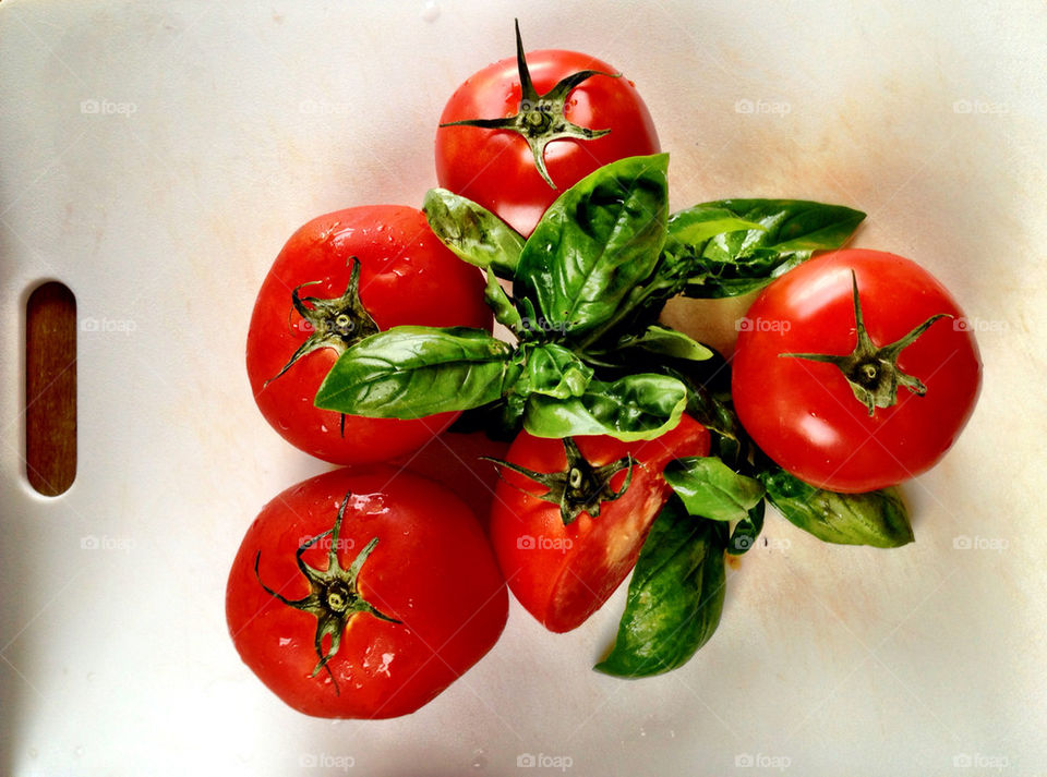 Tomatoes and basil with knife on cutting board