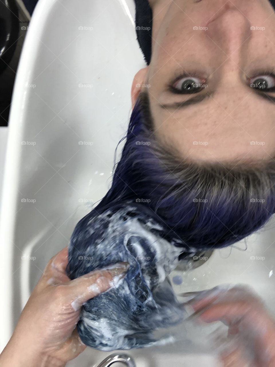 Purple hair color being washed out in sink at a hair salon