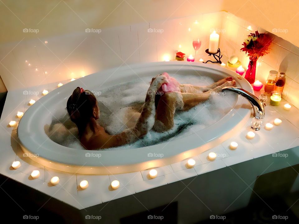 Woman enjoying a luxurious bubblebath by the romantic glow of candlelight.