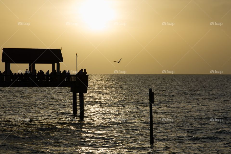 Silhouettes of people on the pier watching the sunset . 