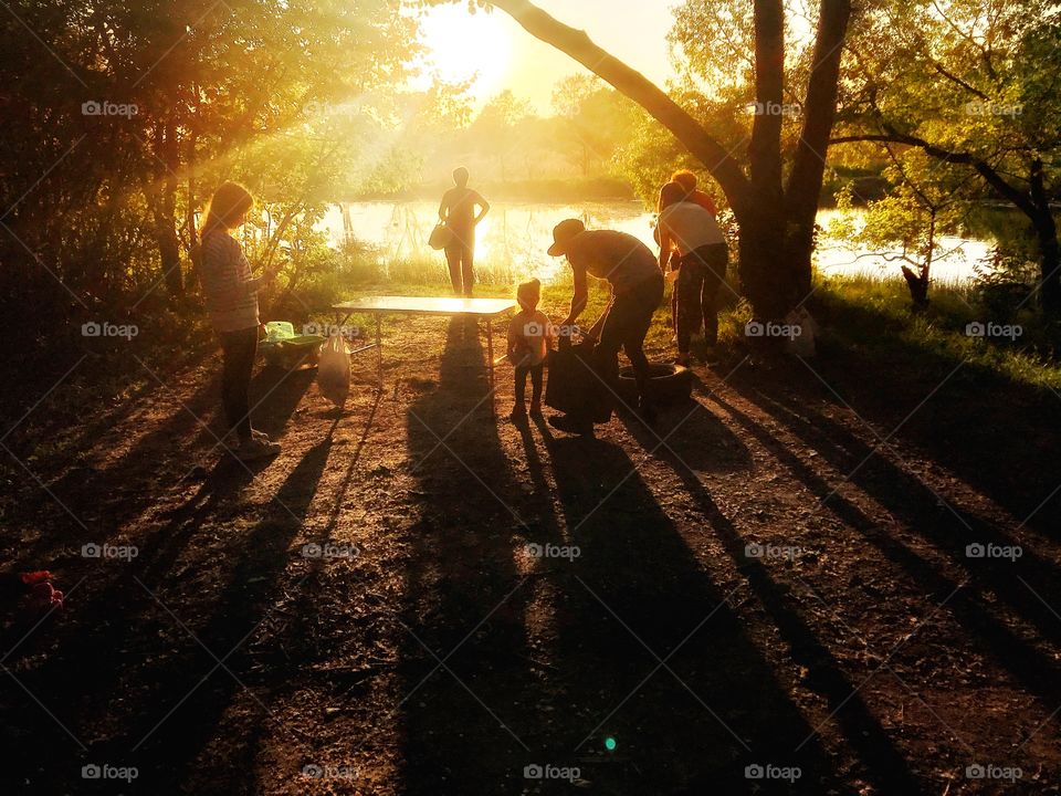 people and their shadows by the lake in the golden rays of sunset