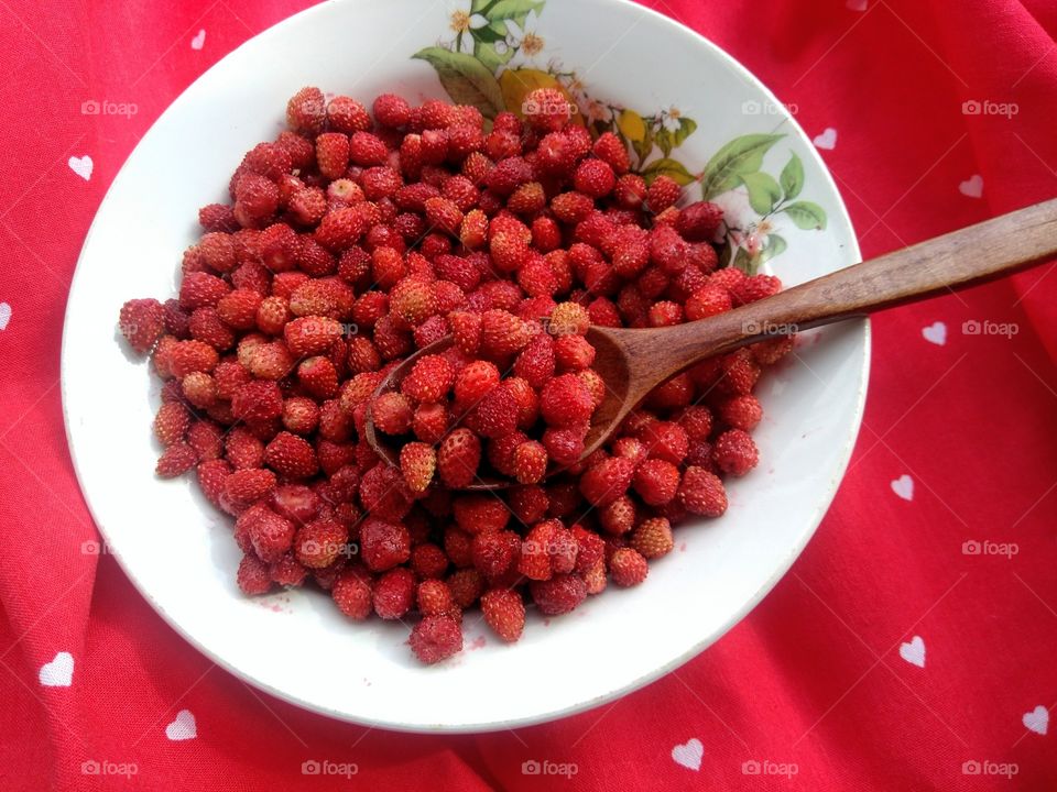 wild strawberries on a plate red background