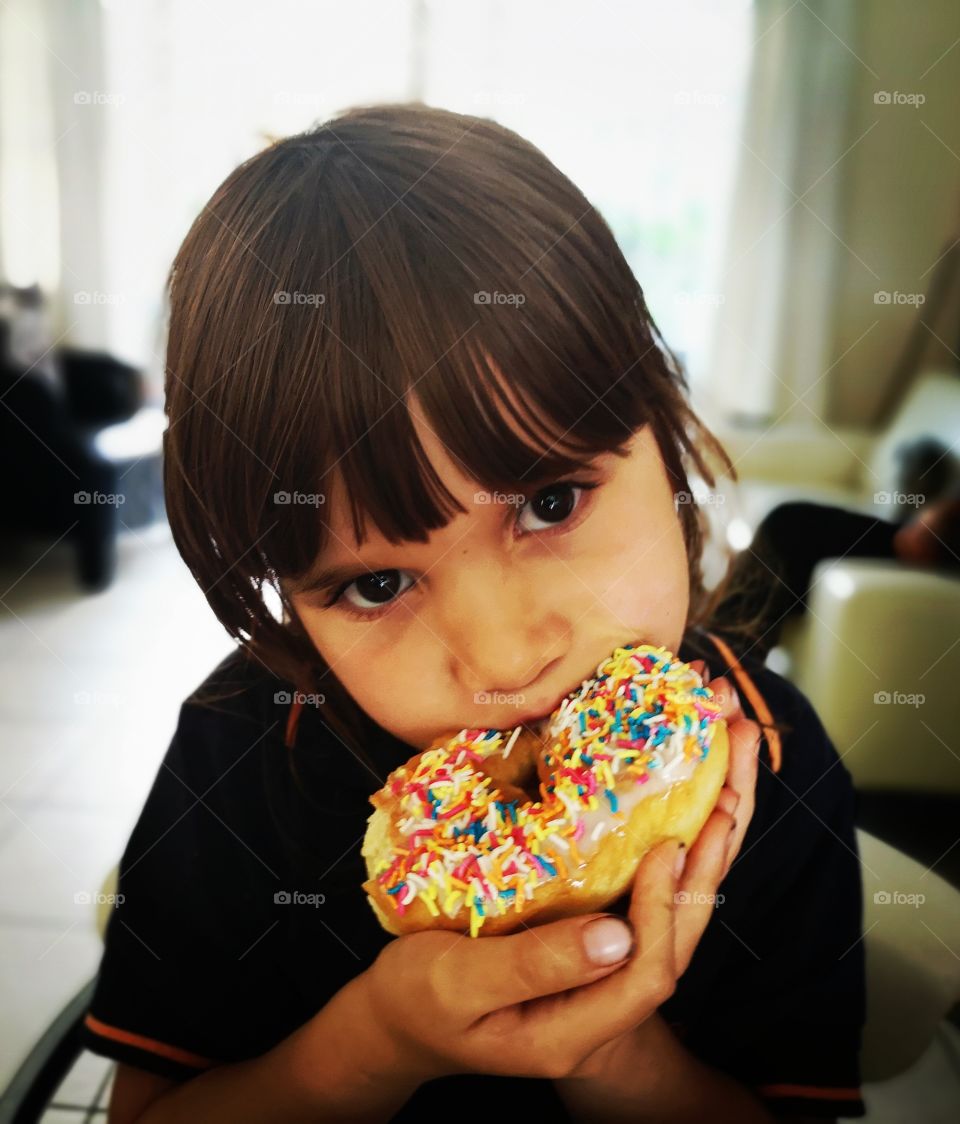Girl close up eating rainbow sprinkled donut