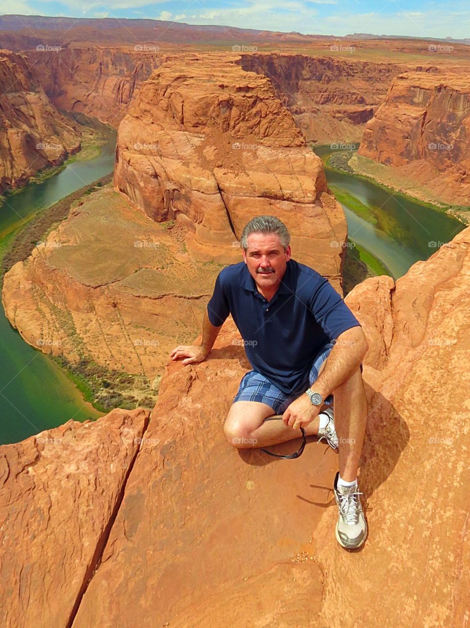 A hiker sitting at the edge of a cliff at Horseshoe Bend in Arizona