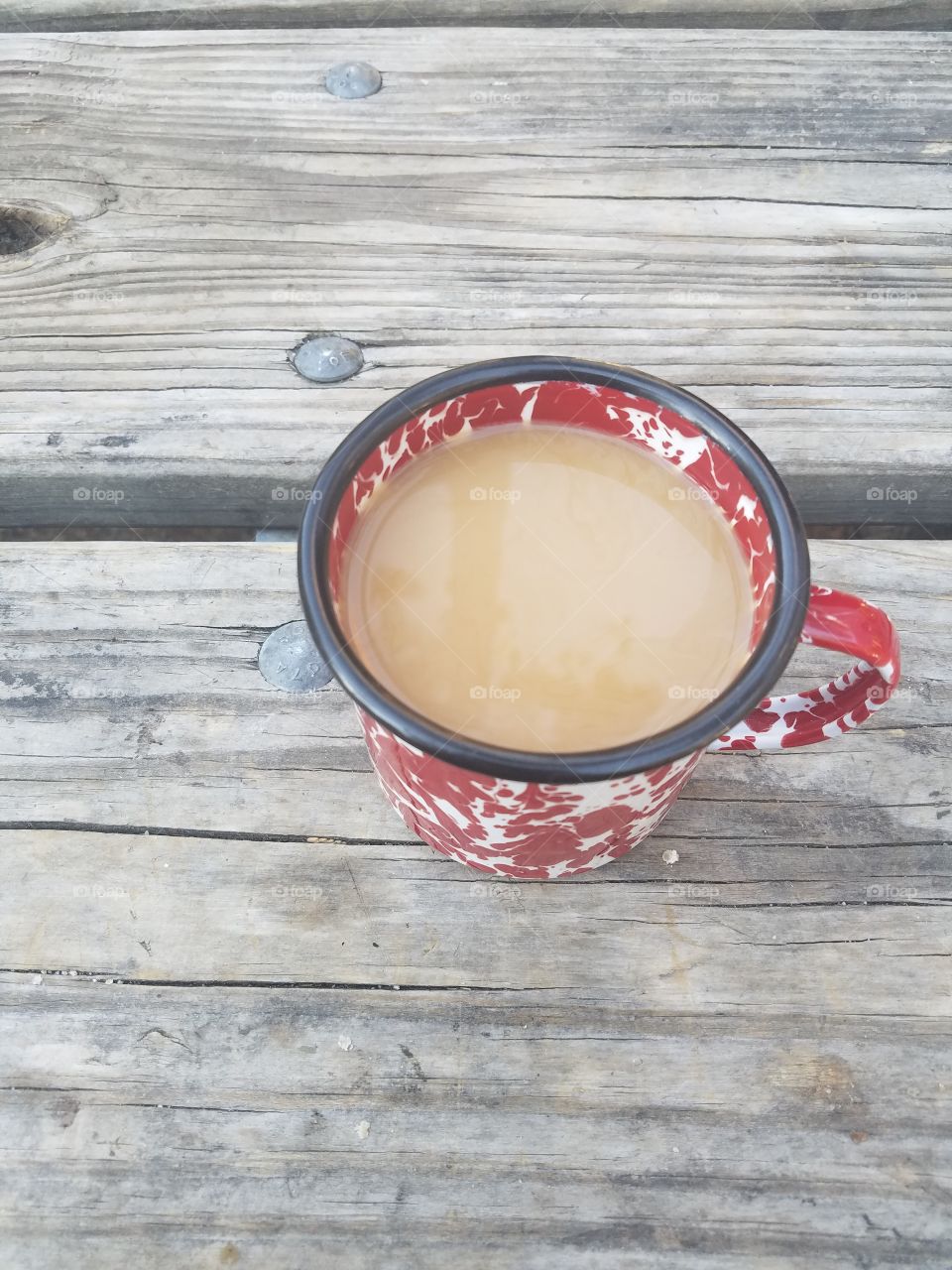 Hot coffee in a camping mug sitting on a picnic table
