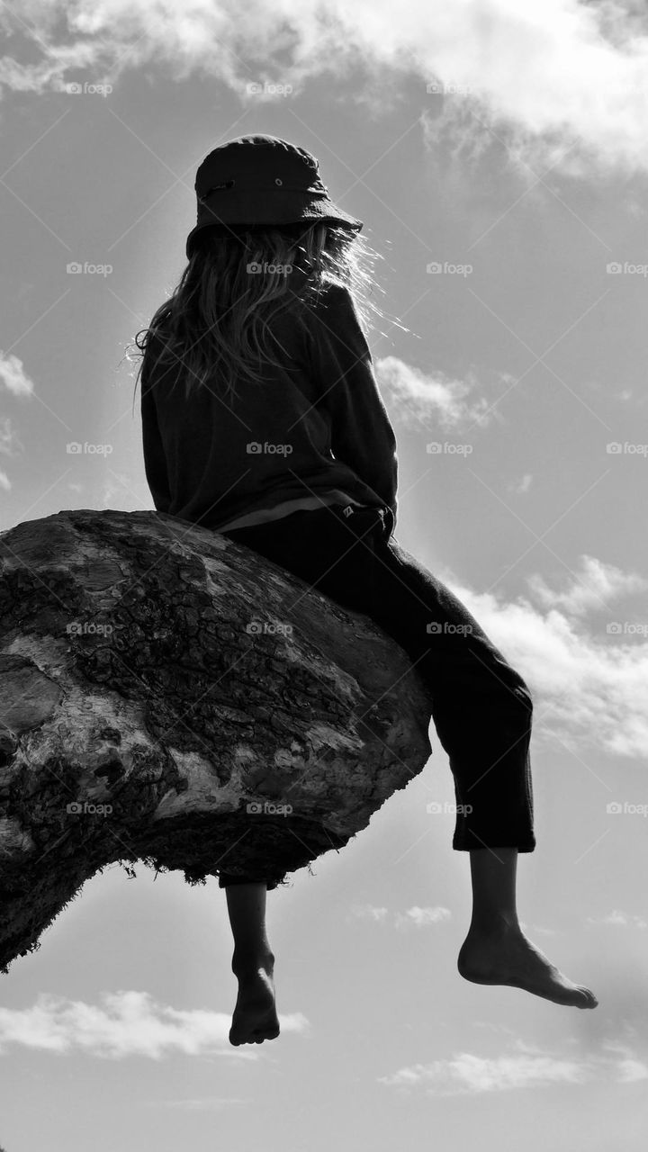 Kid sitting on the end of old tree branch 