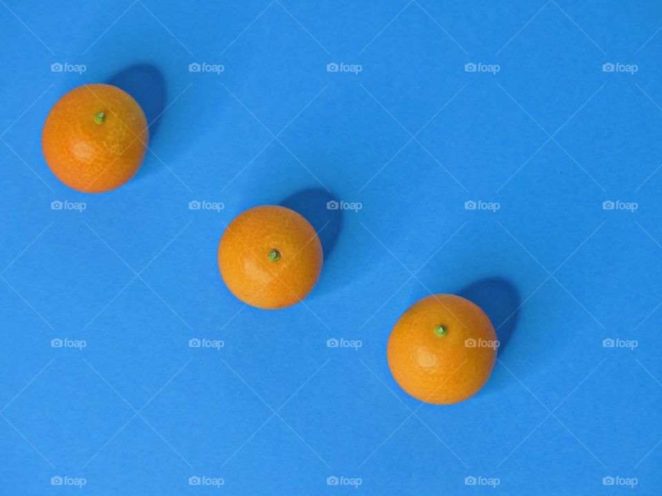 Three delicious kumquats - The Power of Threes - Everything that comes in threes is perfect, or, every set of three is complete, conveys the same idea as the rule of three. Displayed on Bright, colorful backgrounds. 