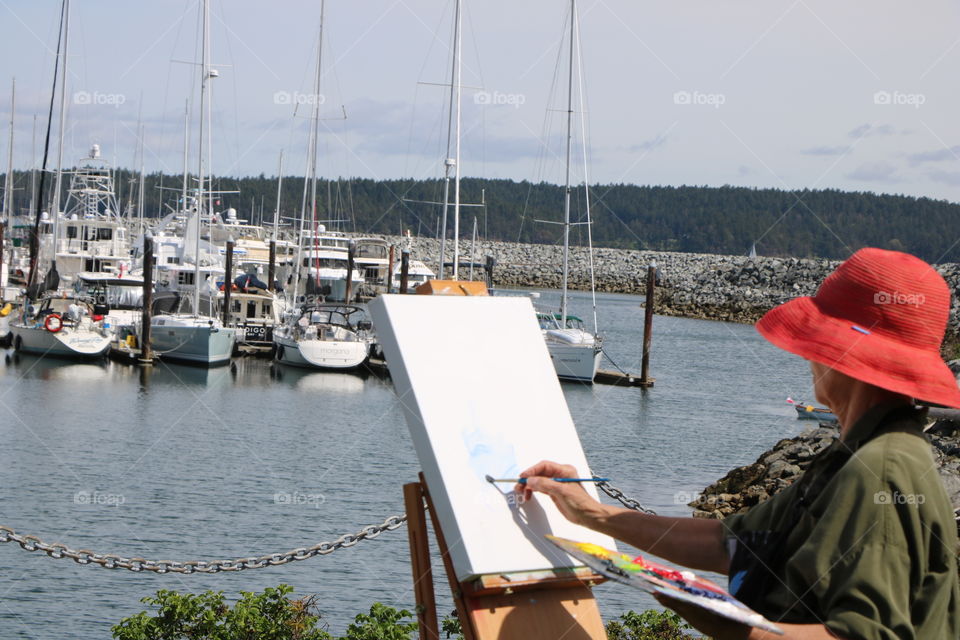 Woman enjoying her painting hobby by the harbor 