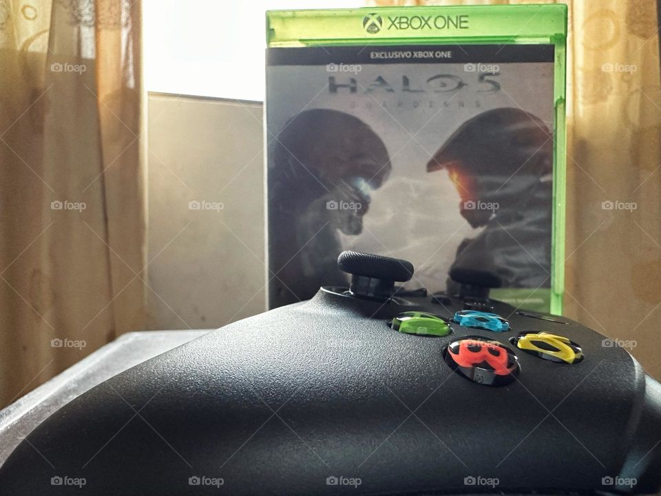 Halo video game box behind of a Xbox controller with natural light at the background.