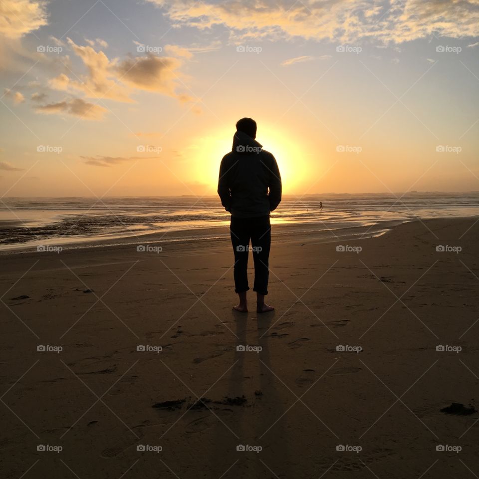 Silhouette of person at sunset by the ocean 