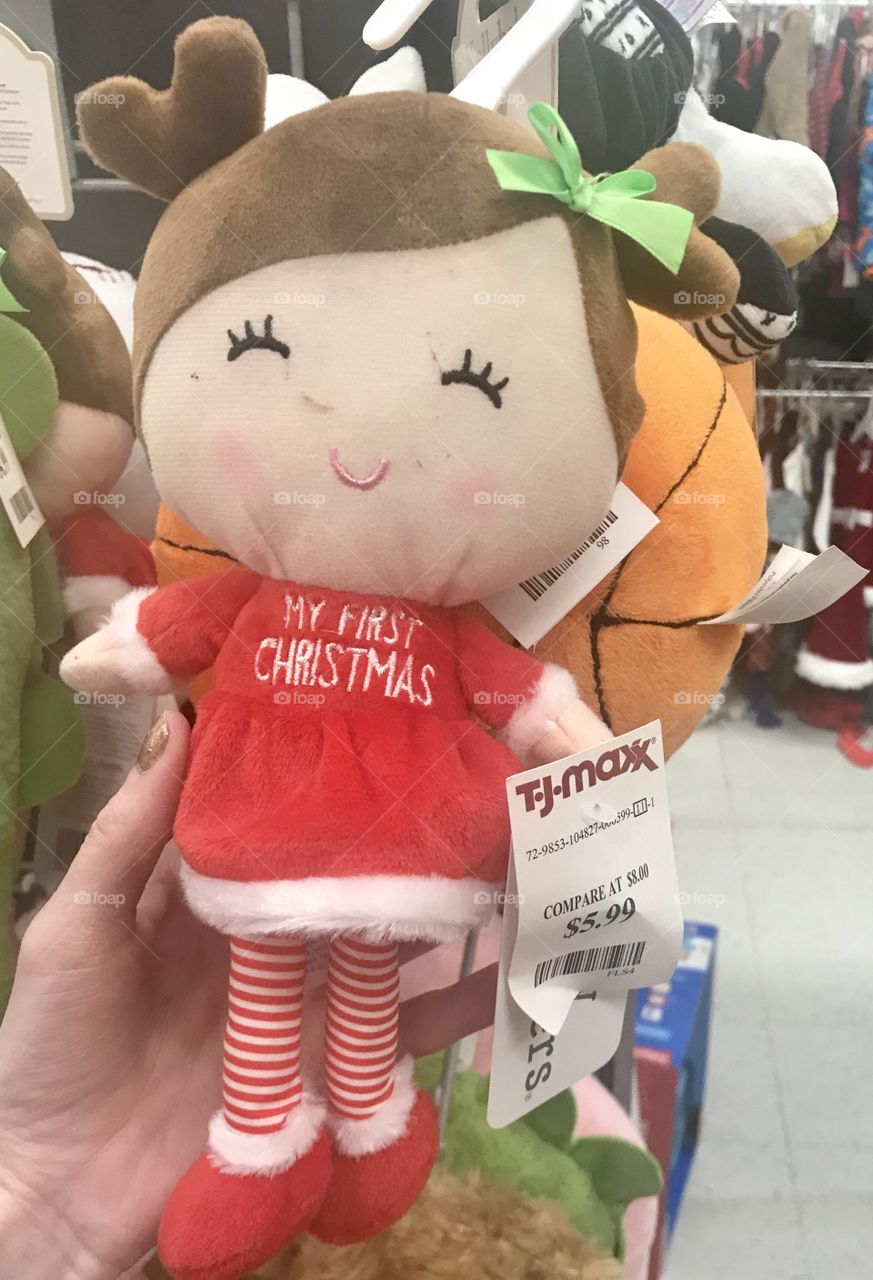 Little Christmas doll wearing a Santa suit and striped red and white stockings for a baby’s first Christmas, toy from TJ MAXX department store. 