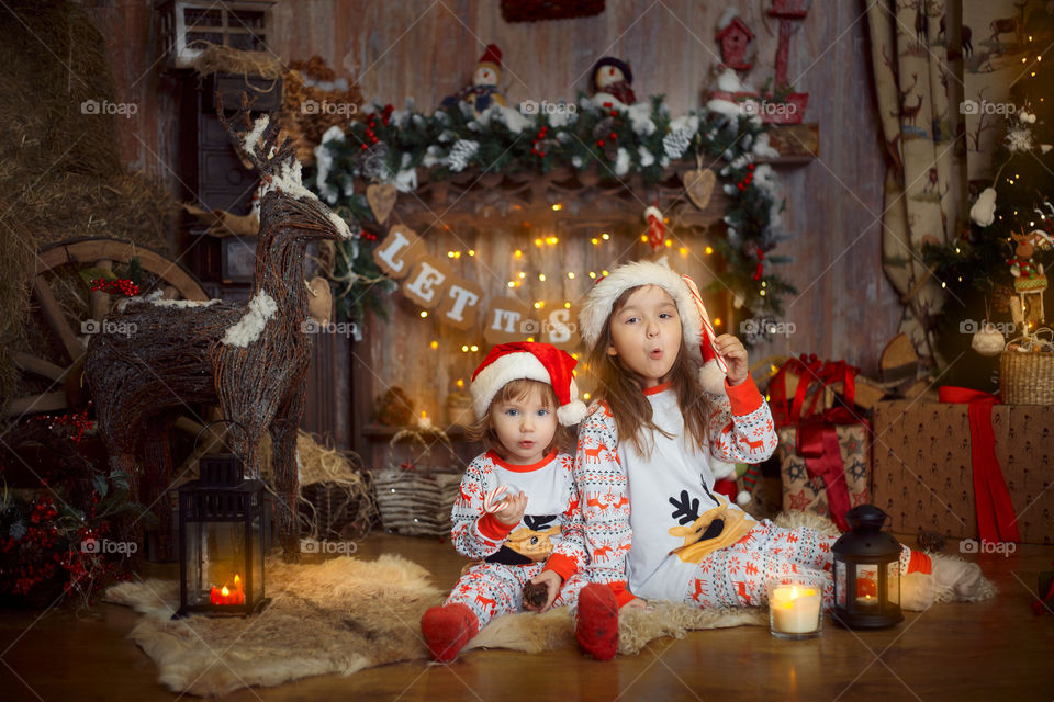 Little sisters near fireplace at Christmas Eve 