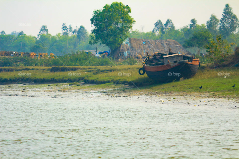 On the murky banks of Bhitarkanika (Orissa, India), where life thrives, consisting amongst it various animal species. It is a hotspot for fishermen as the area consist of backwater which provide a large nutritious environment and hence abundance of fishes can be seen. Here lies a fishing boat/barge, resting to the sides of the river bank after a long day of haul.