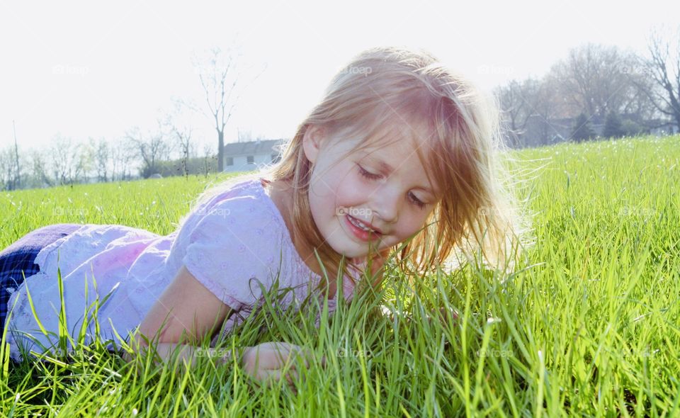Gorgeous photo of little girl laying in tall grass on a beautiful summer afternoon with sunlight at her back!! 