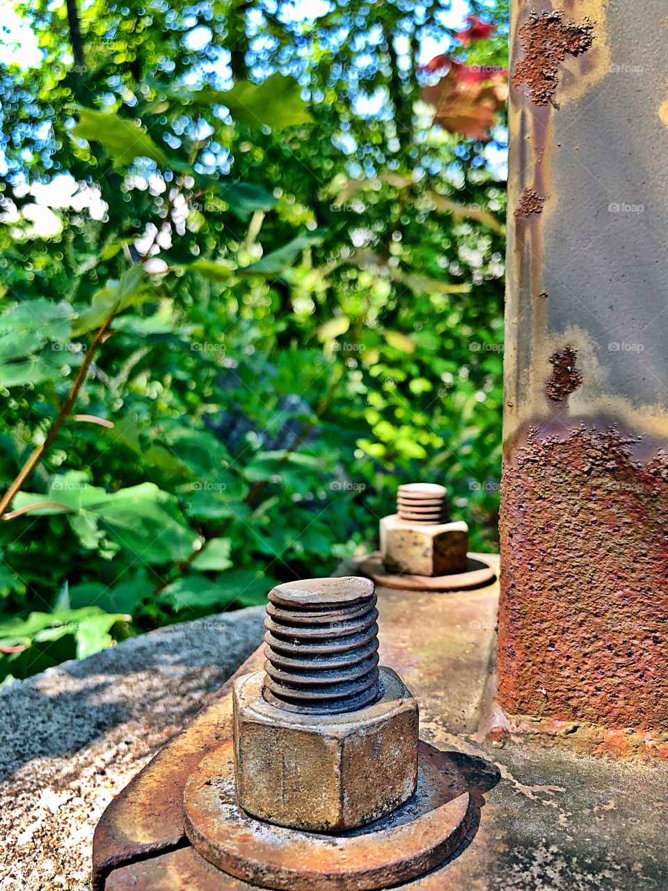 Rusted bolts/screws and nuts on a rusty steel structure attached to a concrete block. Rusty texture 