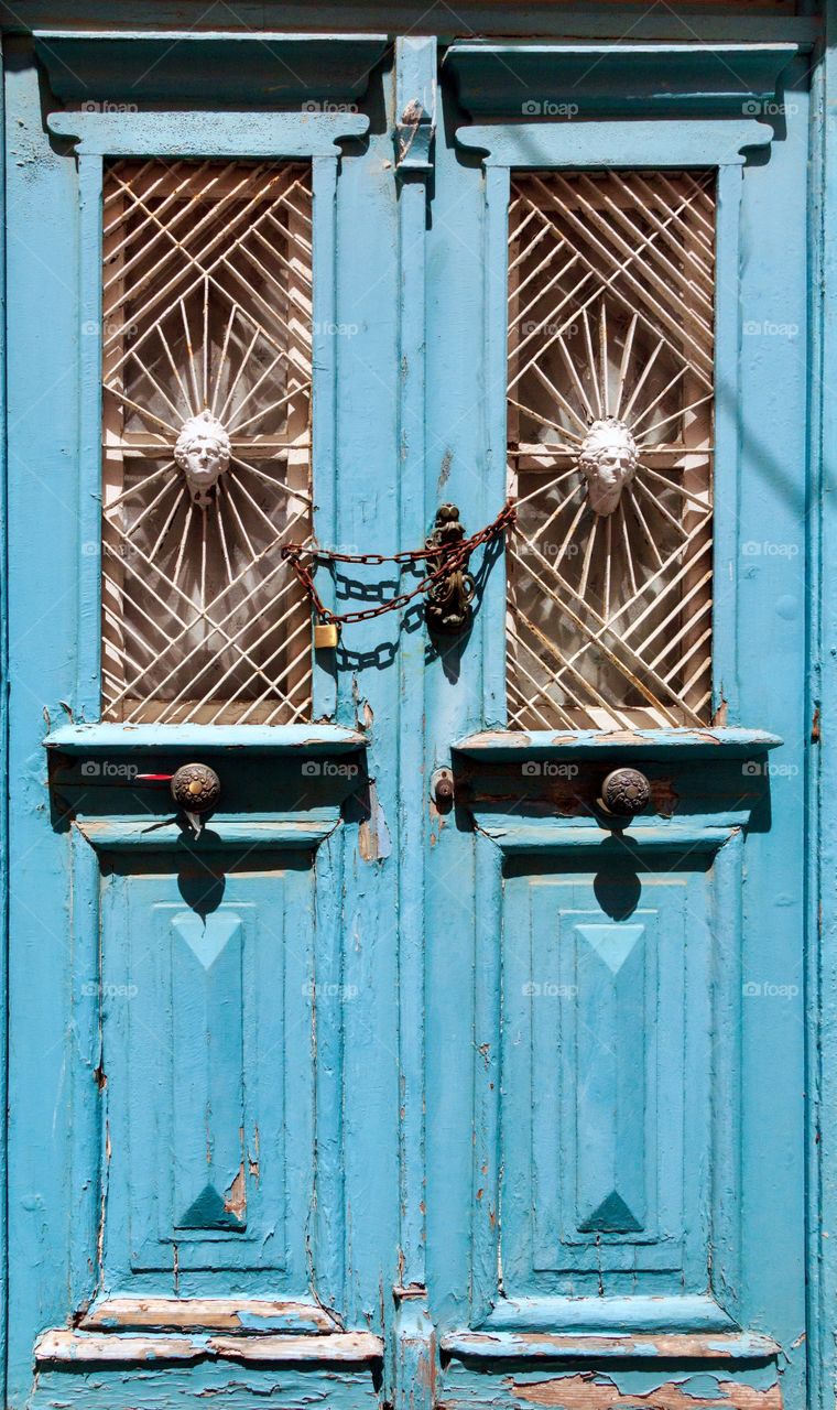 Old wooden door with metal ornaments and iron door handle, looked with chain and padlock
