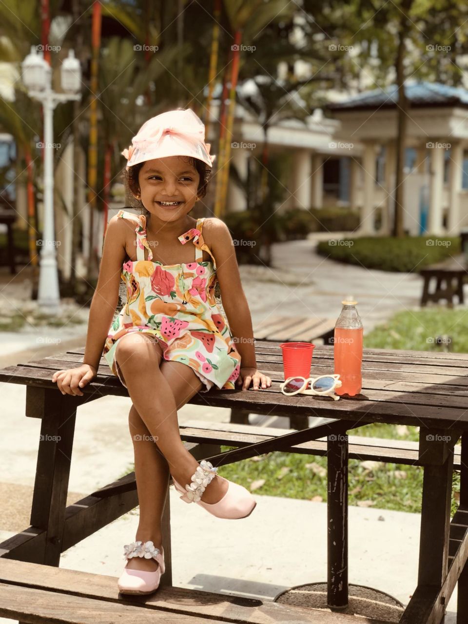 Cute little funky model sitting on outdoor wooden table with crazy style and smiling 