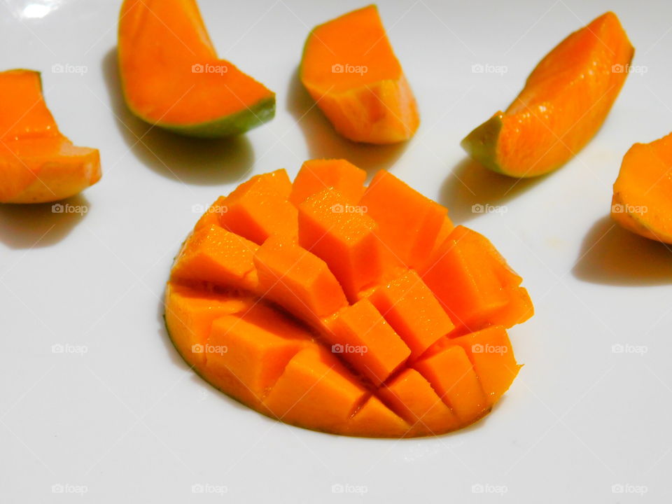Carved mangoes isolated on a white background,Half cut ripen mango with square design surrounded by mango slice on white background.Lockdown photography in May,June Month.