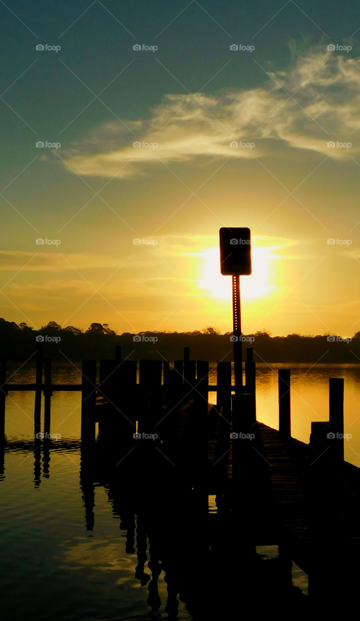 Silhouette pier on lake at sunset
