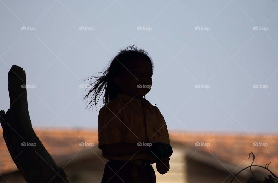 The hair's blown by the wind. The teens female elementary school after got the times for went home from school. The girls coming to mw in distance of enouht for capturing . She was coming with her friend, a boy . They got for attitude as a teens .