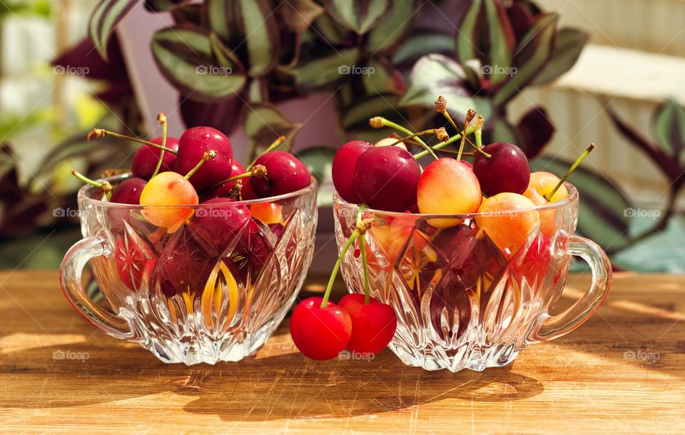 Two crystal cherry cups on a wooden table.