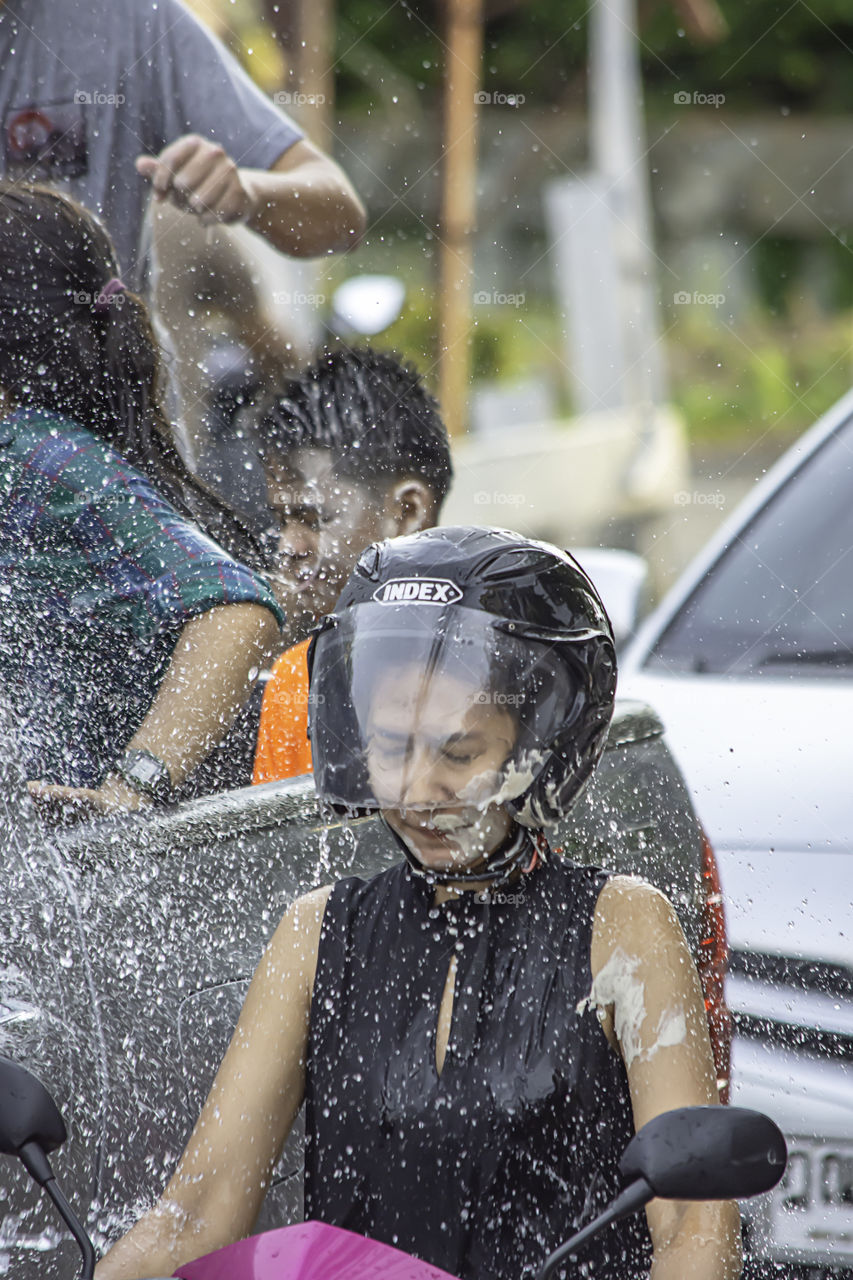 Asian woman Riding a motorcycle play water and flour in Songkran festival or Thai new year in Thailand at Bang kruai, Nonthaburi , April 15, 2019