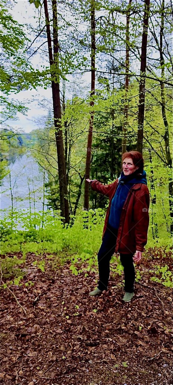 This young lady holds out her hand to see how much rain is coming down through the trees by „Eging“ in the „Bayerischer Wald“, the „Bavarian Forest“ in Germany. In good spirits she won’t let the moisture spoil her fun. 2024. Hypnotic Productions