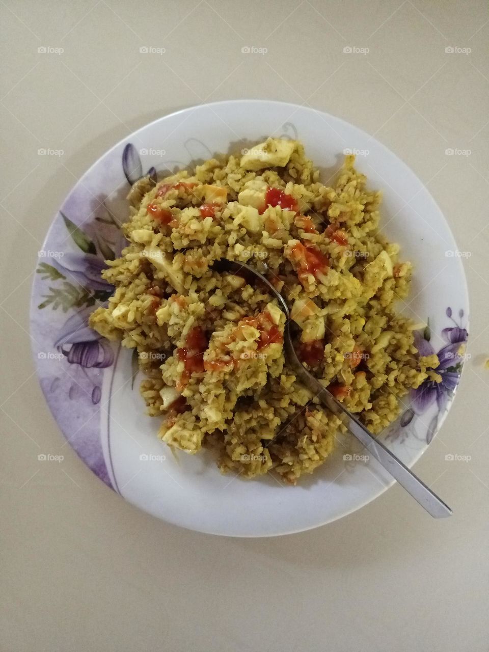 Beautiful white and purple colour combination dish plate on the table with hot and testy egg rice garnish with red colour tomato sauce it was so testy yummy