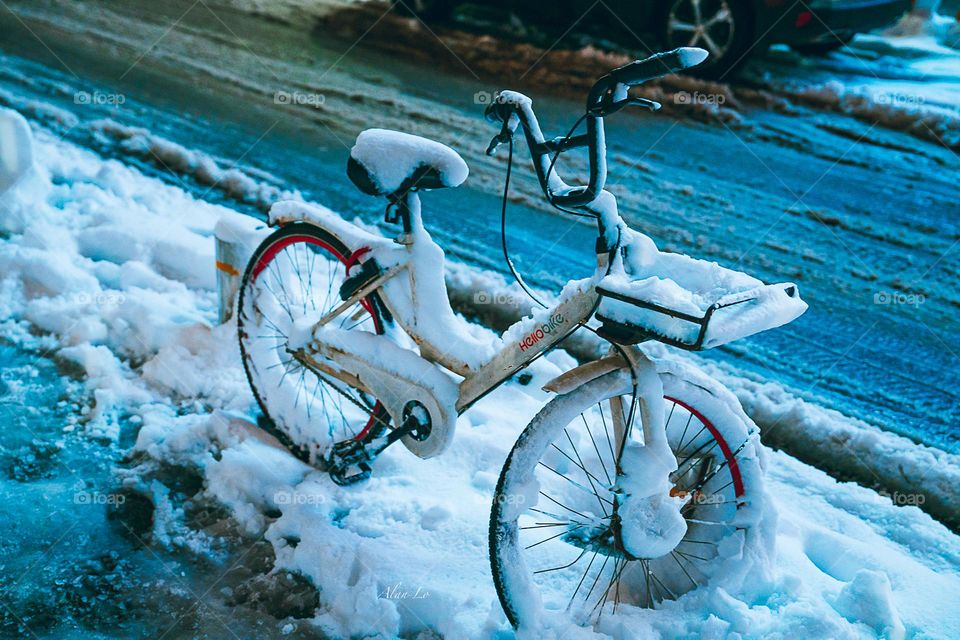 A bicycle covered by snow