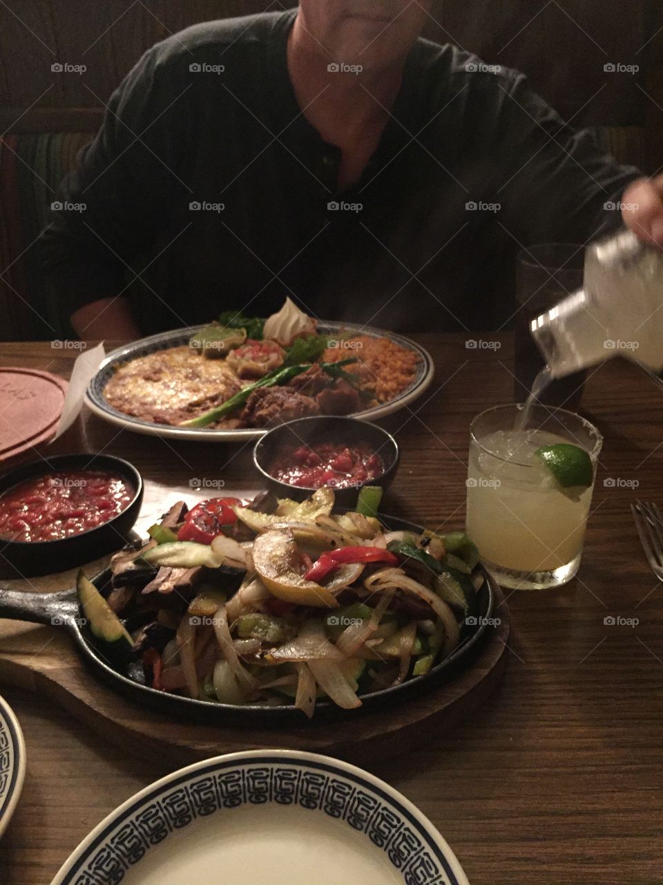 Staying warm inside with steamy hearty dinner meal of Mexican fajitas, rice, beans, veggies, and margarita cocktail mixed drink