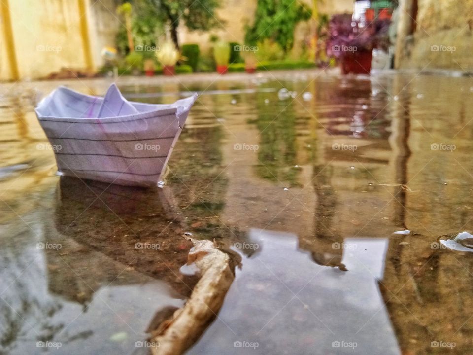 A paper boat on a small water puddle